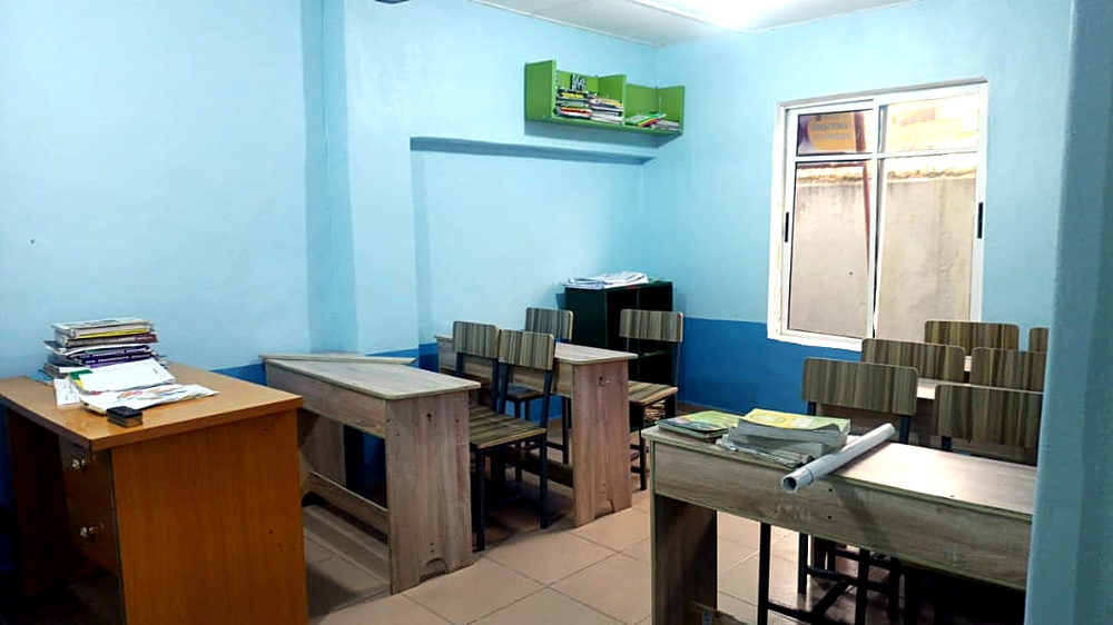 Classroom with wooden desks and book shelves at Flourish Playhouse